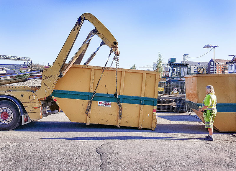 Miljöarbetare lastar av container med liftdumper